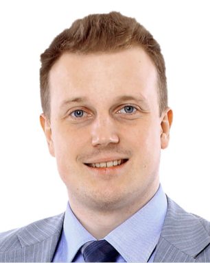 a man in a suit and tie smiling at the camera.