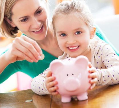 a woman and a little girl holding a pink piggy bank.